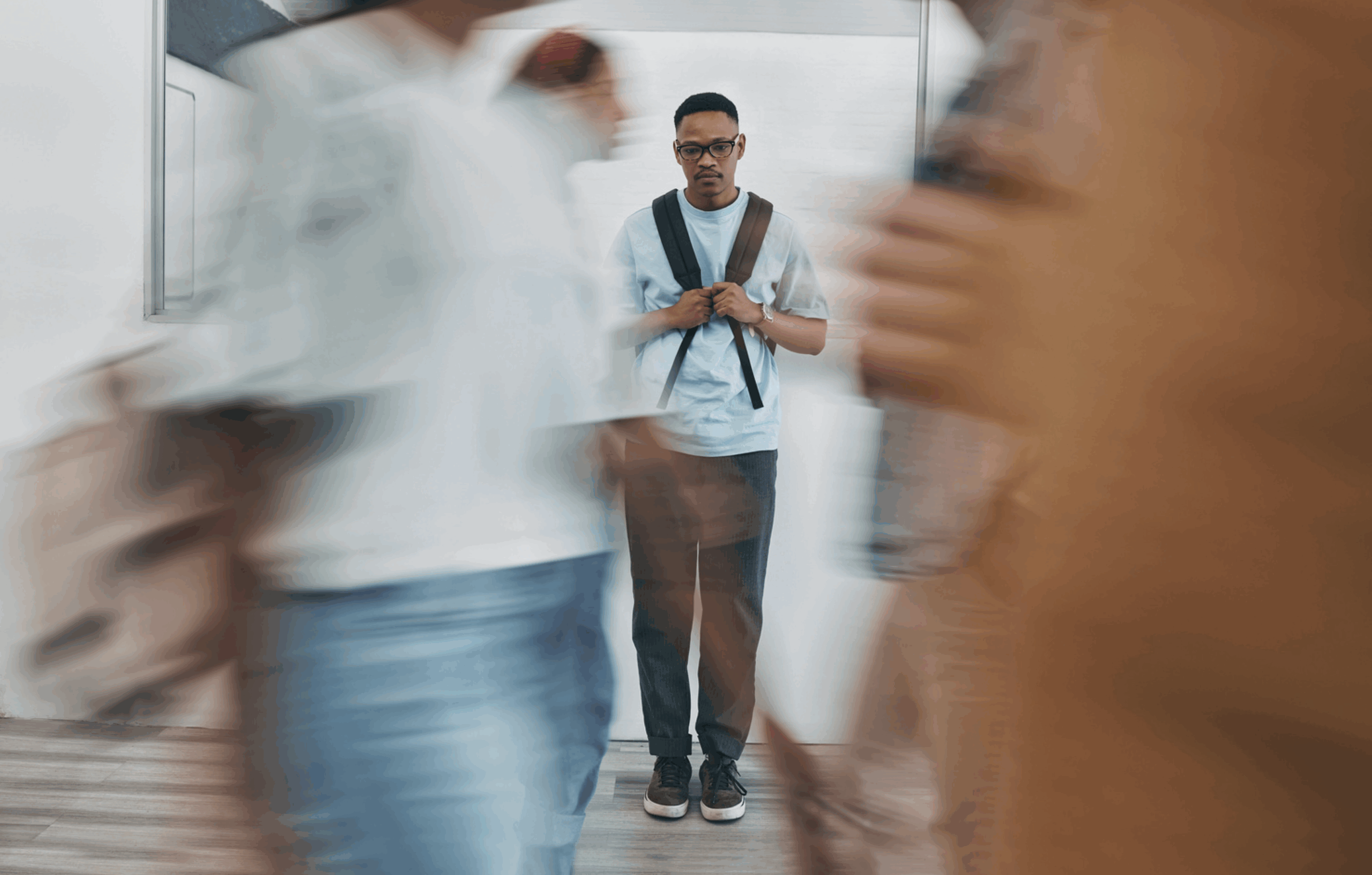 Person standing still in a crowded hallway with blurred motion around them, symbolizing the emotional disconnection and overwhelm of high-functioning freeze.