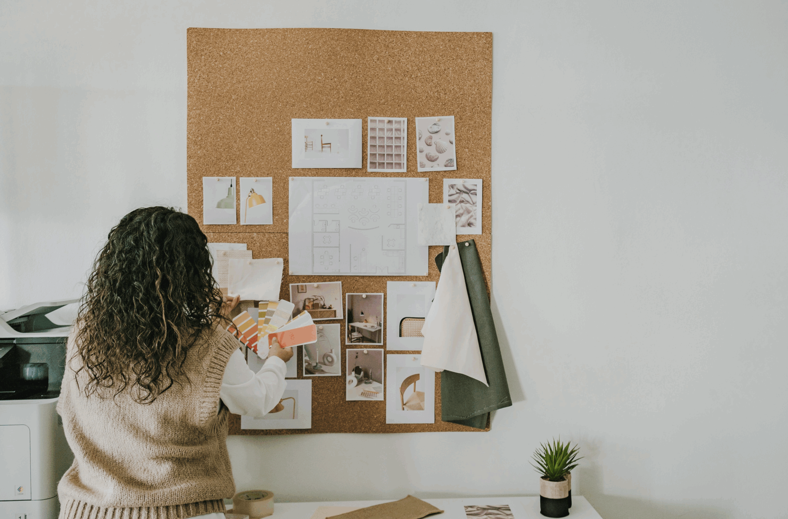 Woman creating a vision board with sketches and color swatches, symbolizing intention, creativity, and taking action toward big dreams. Overcoming fear.