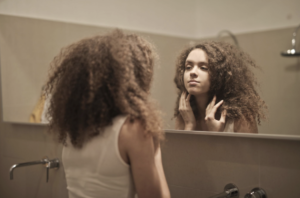 Woman looking in the mirror while reflecting on self gaslighting and learning to trust herself